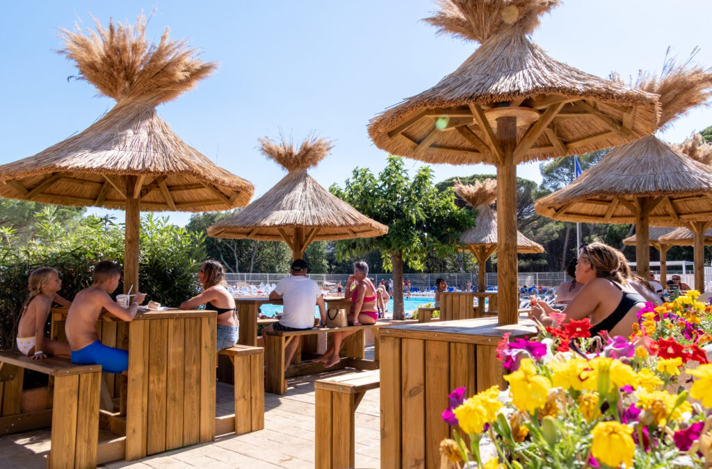 Oasis Village snackbar op het terras bij het zwembad, tafels onder rieten parasols bij het zwembad