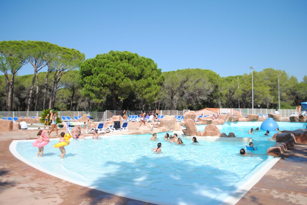 Het zwembad van Oasis Village, met tegenstroom, een onderwaterstrand en rotsachtige decoratie onder de pijnbomen