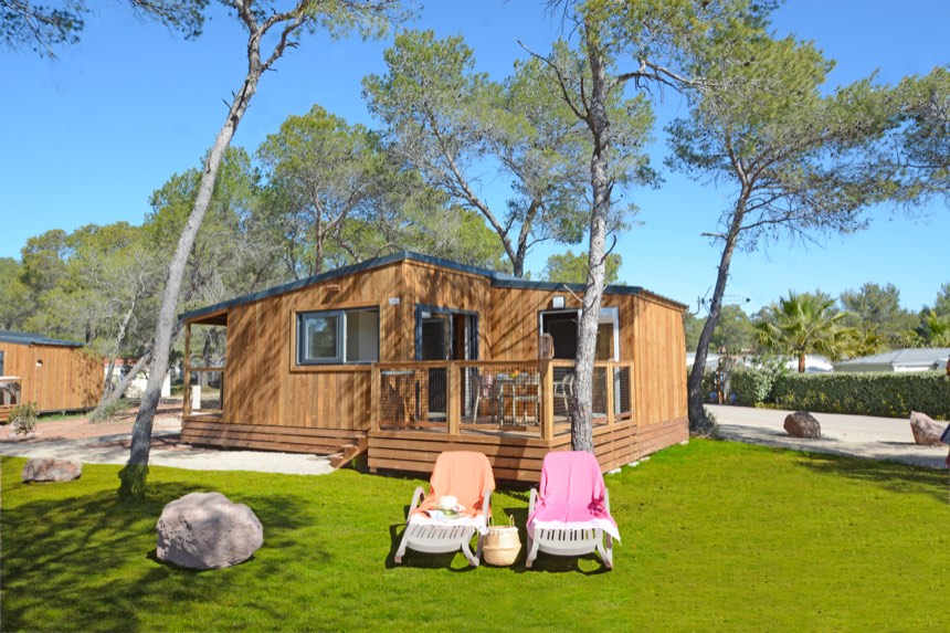 Hochwertiges Holzchalet unter Pinien, mit Rasen und Sonnenliegen
